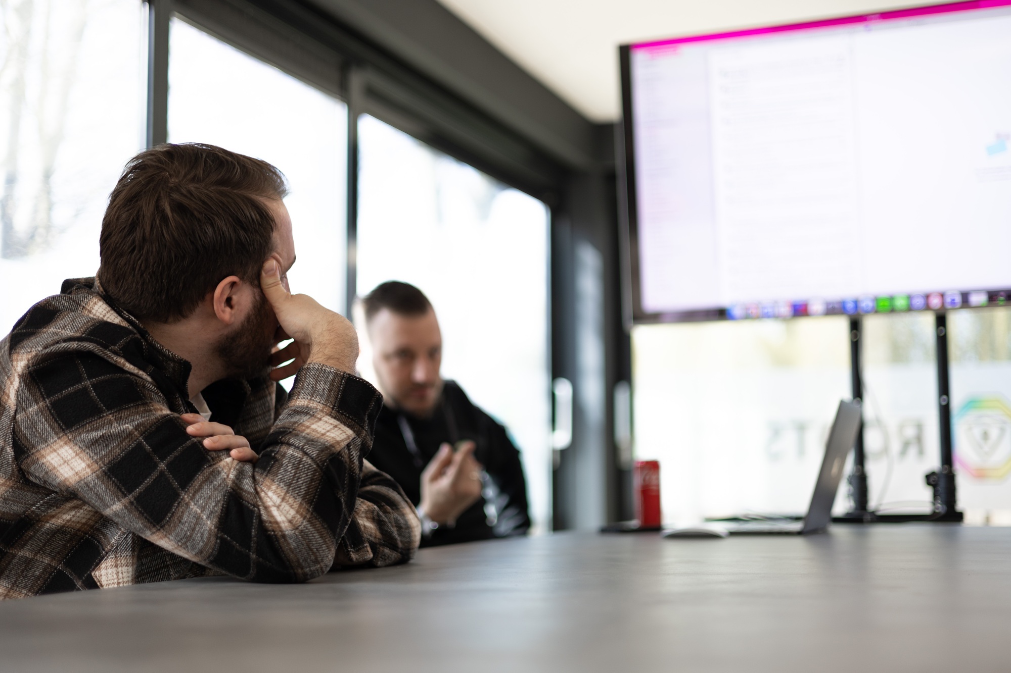 Two colleagues reviewing a phishing campaign on a wall display in the Rootsec meeting room