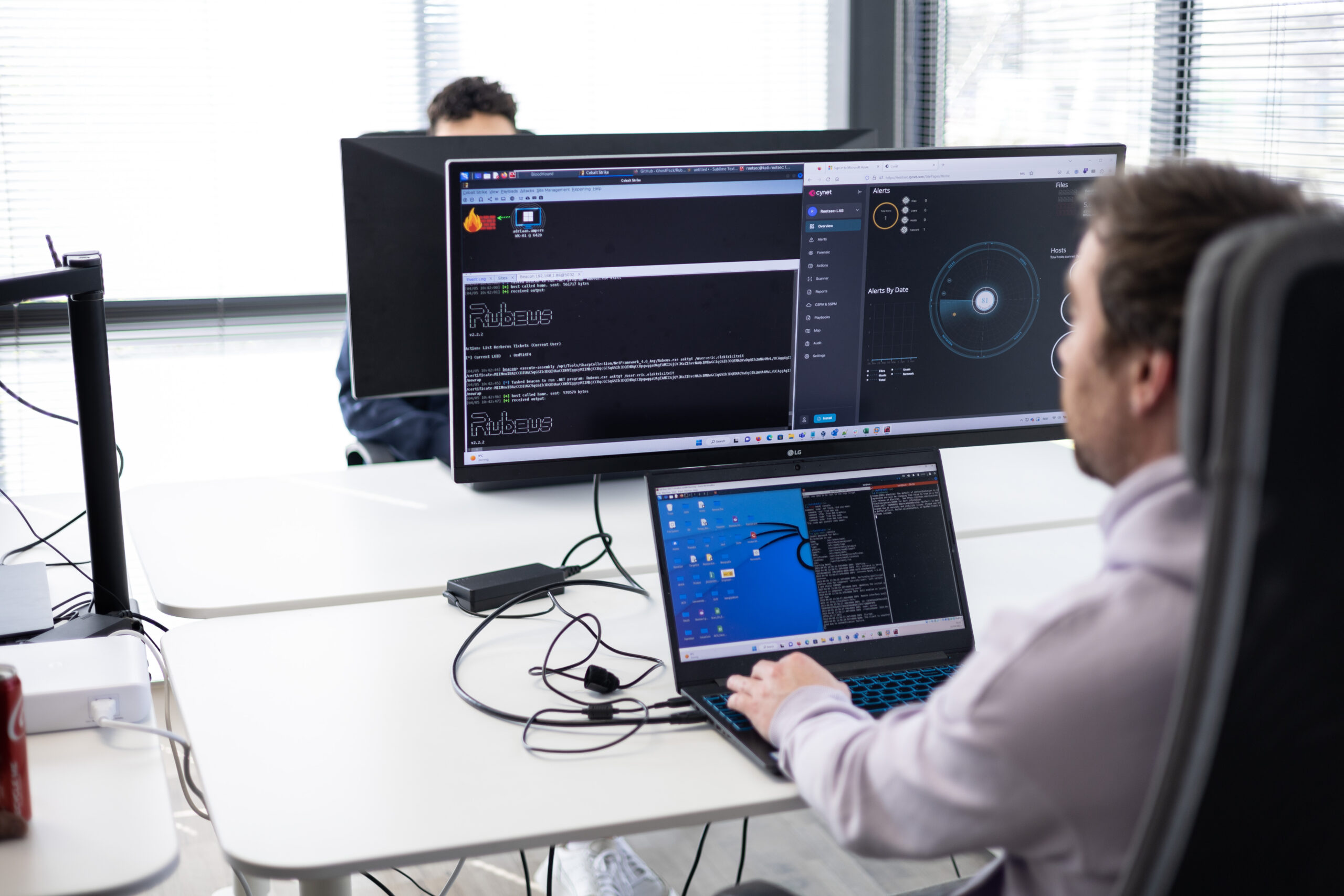 Red team operator working across a wide monitor and laptop during an adversary simulation